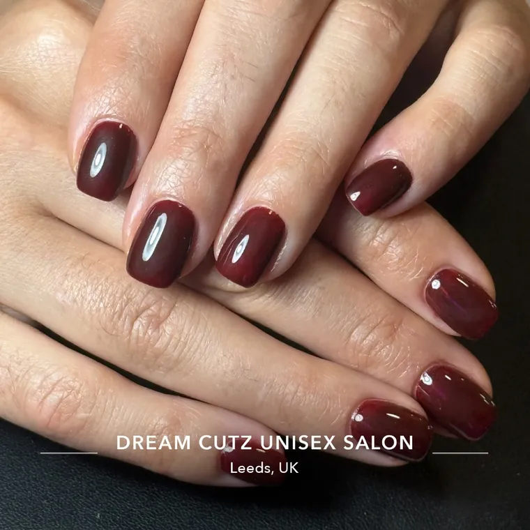 A rich burgundy set of almond-shaped acrylic nails
